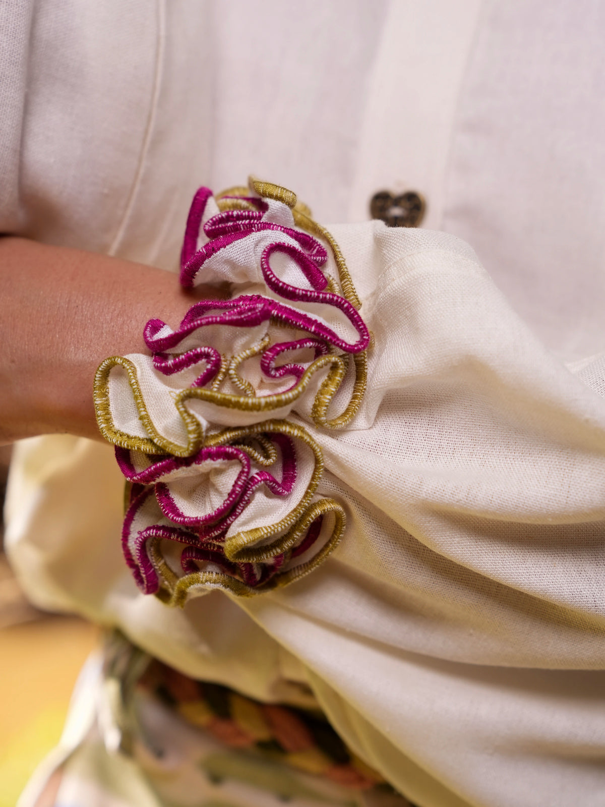 Primer plano del volante fucsia y dorado en el puño de la Blusa Travesía en lino crema – Ale Ardila Studios